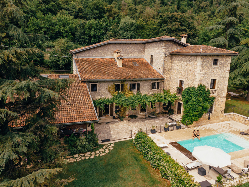 aerial view of couple resting at swimming pool near villa in Italy